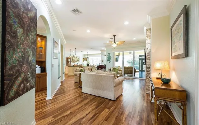 a living room with couches and kitchen view with wooden floor