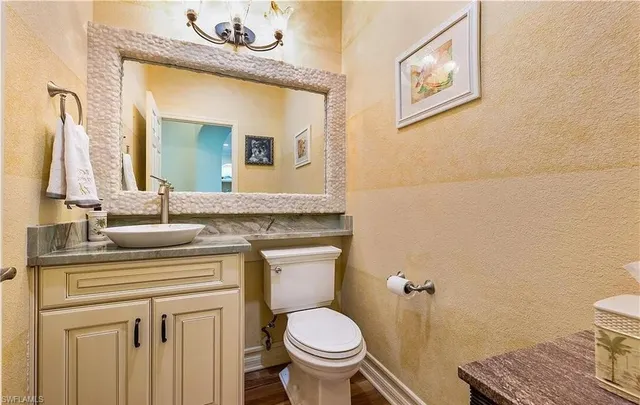 a bathroom with a granite countertop toilet sink and mirror