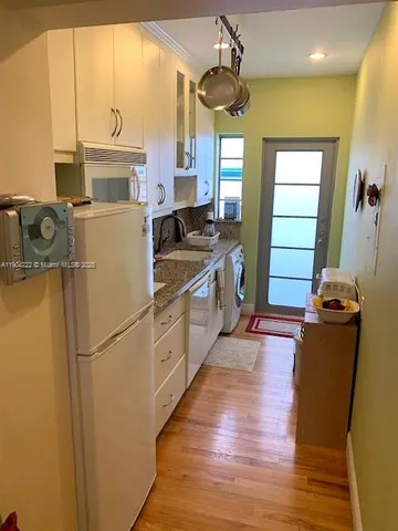 a kitchen with sink a refrigerator and wooden floor