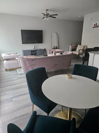 a living room with furniture a flat screen tv and kitchen view
