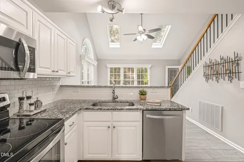 a kitchen with stainless steel appliances granite countertop a refrigerator sink and white cabinets