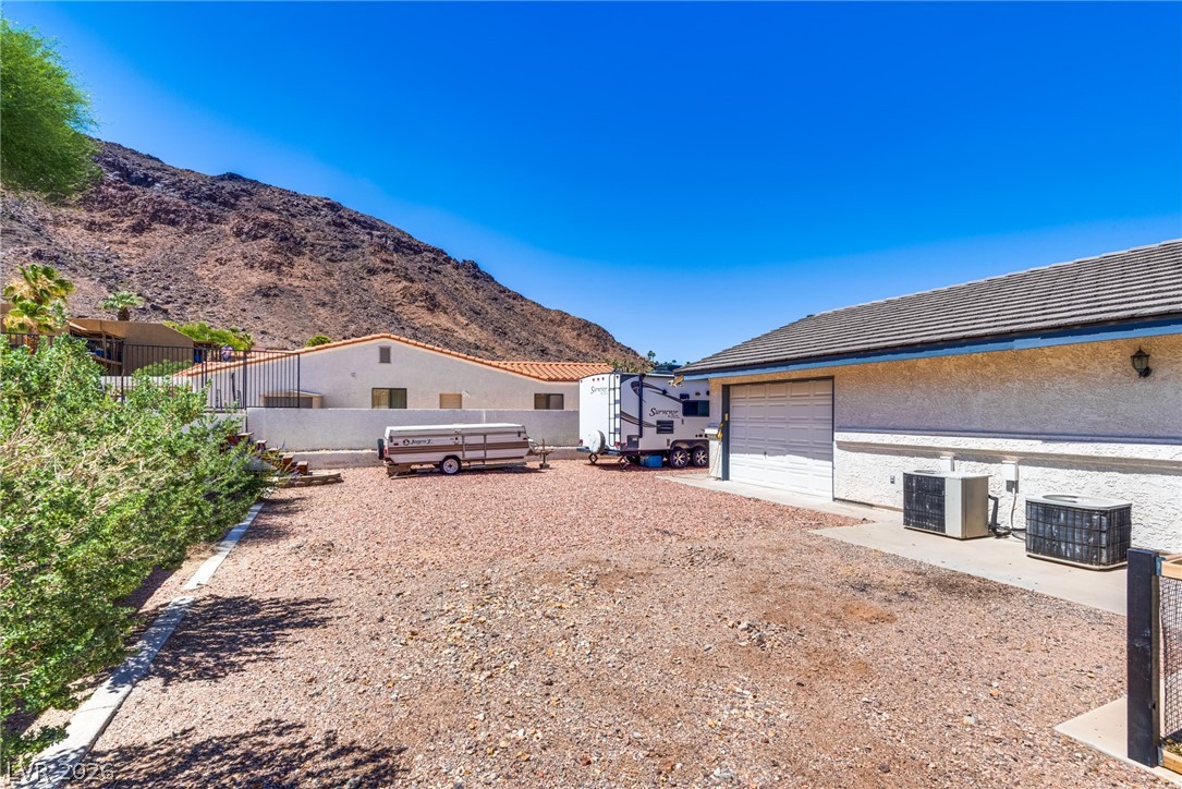 524 Swallow Cove Boulder City, NV 89005 - Photo 46 of 58 A spacious gravel parking area offers ample room for vehicles, set against a dramatic mountainous backdrop.