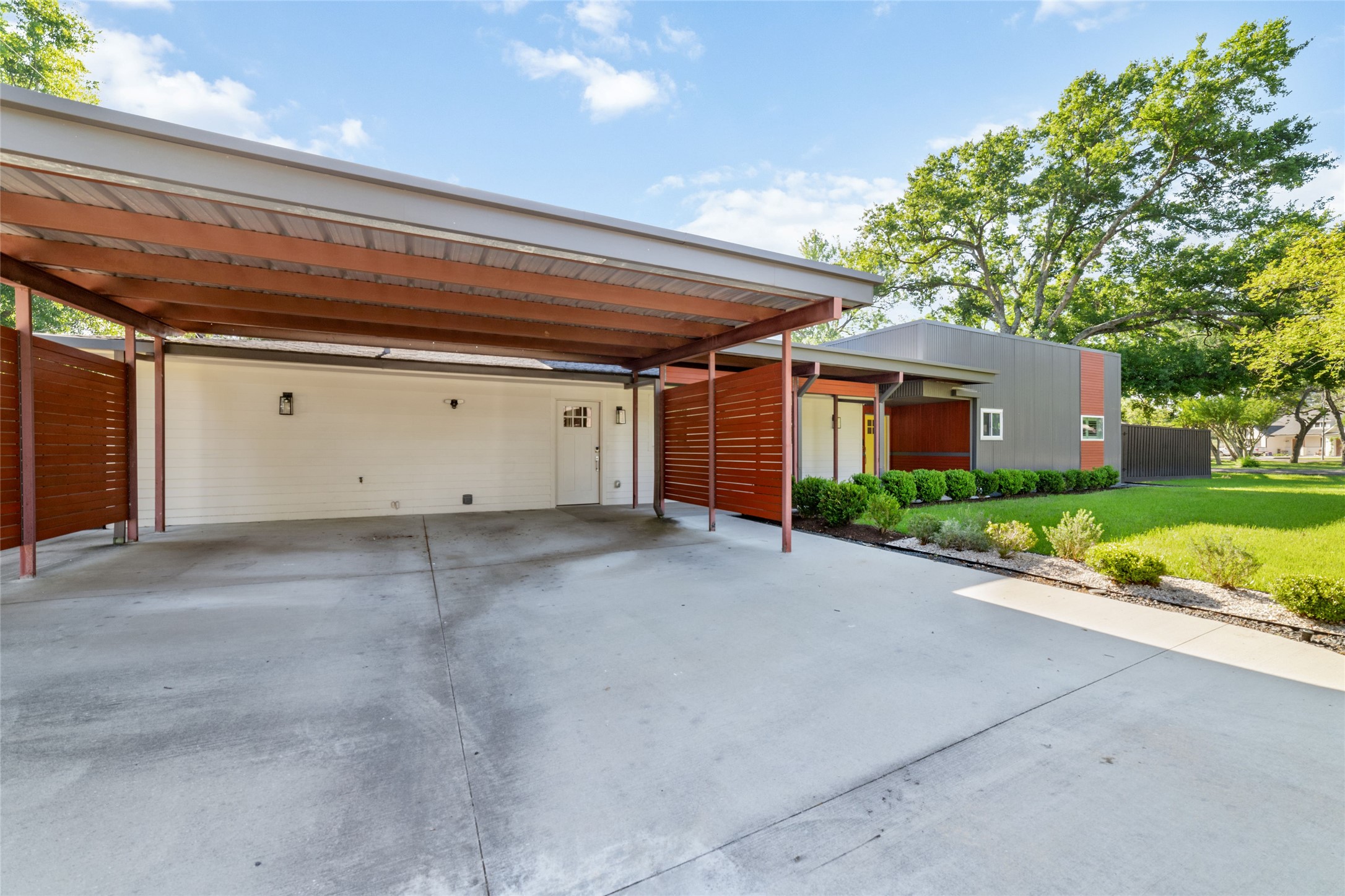 9400 Spring Branch Drive Houston, TX 77080 - Photo 7 of 45 Spacious modern carport with sleek design elements, adjacent to a home featuring clean lines and lush landscaping.