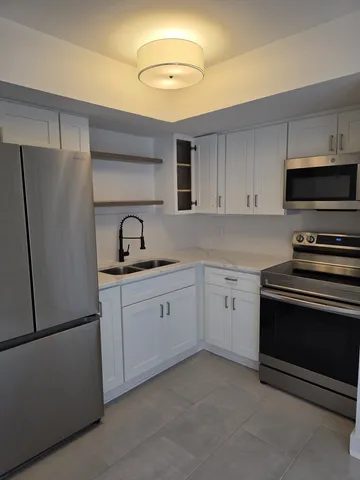 a kitchen with white cabinets and stainless steel appliances