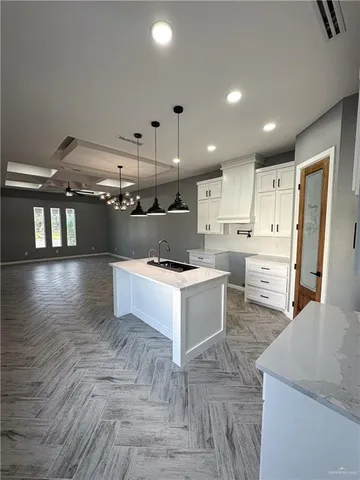 a large white kitchen with lots of counter space wooden floor and stainless steel appliances