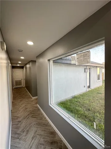 a view of an empty room with window and wooden floor