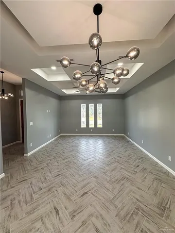 a view of a livingroom with a chandelier fan and kitchen view