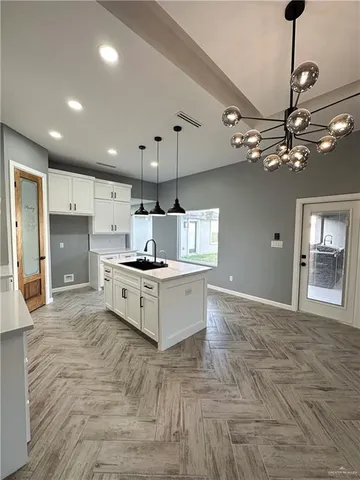 a large white kitchen with a refrigerator a stove top oven a sink and a chandelier