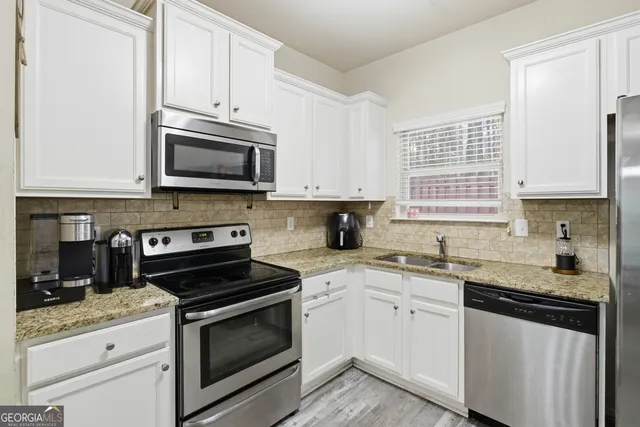 a kitchen with stainless steel appliances granite countertop a refrigerator and a stove top oven