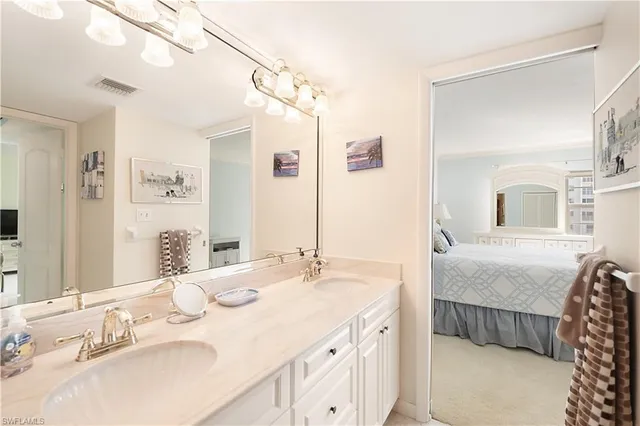 a bathroom with a granite countertop double vanity sink and mirror