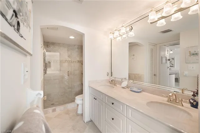 a bathroom with a double vanity sink mirror double shower and a toilet