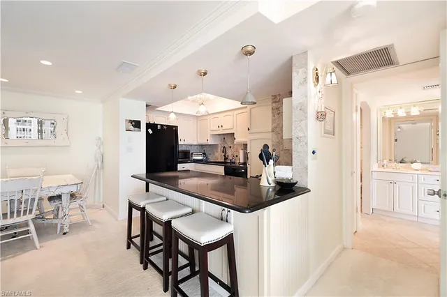 a kitchen with stainless steel appliances kitchen island granite countertop a table chairs sink and cabinets
