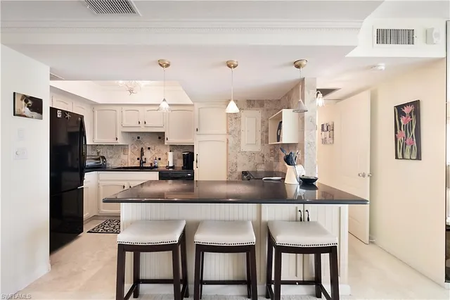 a kitchen with stainless steel appliances granite countertop a dining table chairs refrigerator and sink