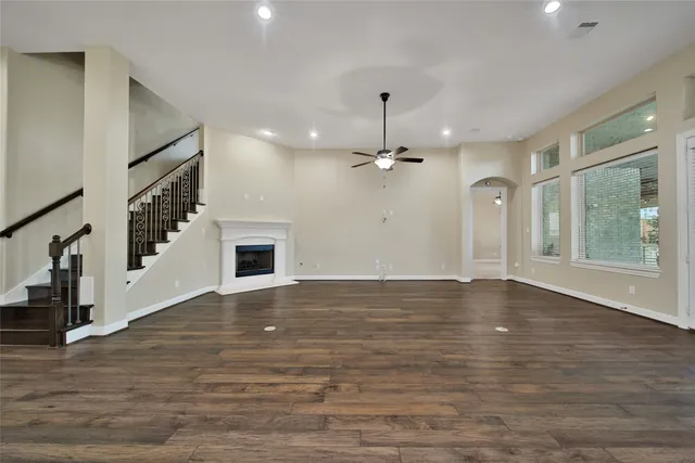 an empty room with wooden floor fireplace and windows