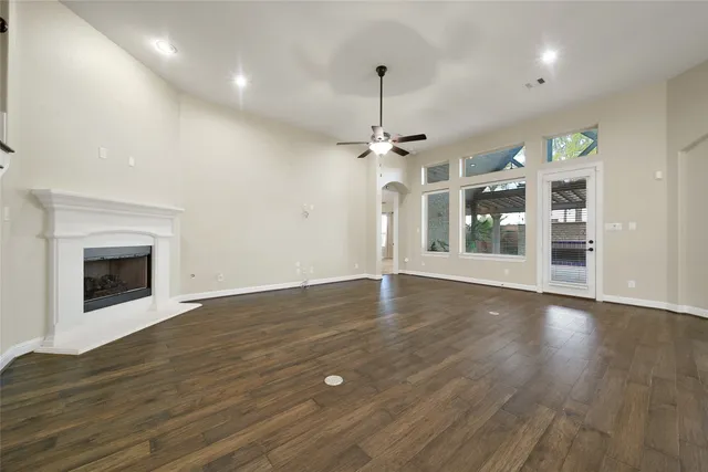 a view of an empty room with wooden floor staircase and a kitchen