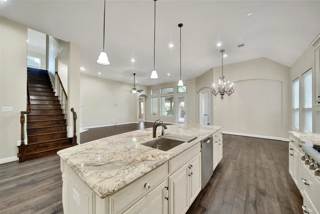 a large kitchen with kitchen island a island a sink stainless steel appliances and wooden floor