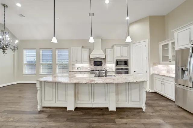 a kitchen with stainless steel appliances kitchen island granite countertop a stove a sink and a refrigerator