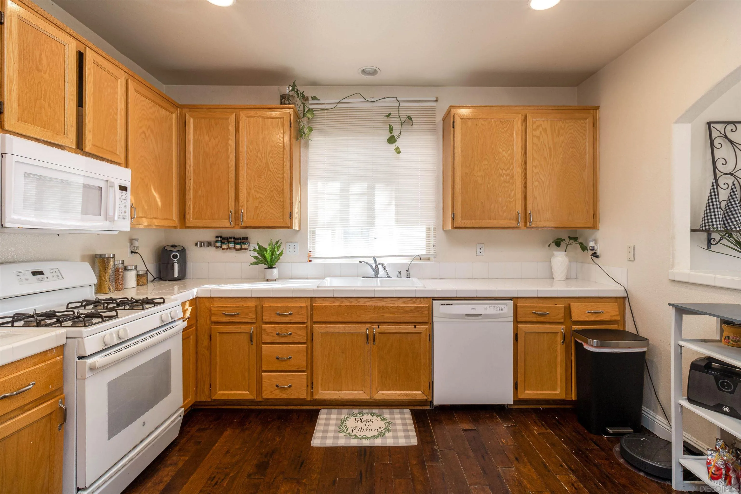 4046 Craven Road, Unit 42 Oceanside, CA 92057 - Photo 4 of 17 a kitchen with stainless steel appliances a sink wooden floor and a window