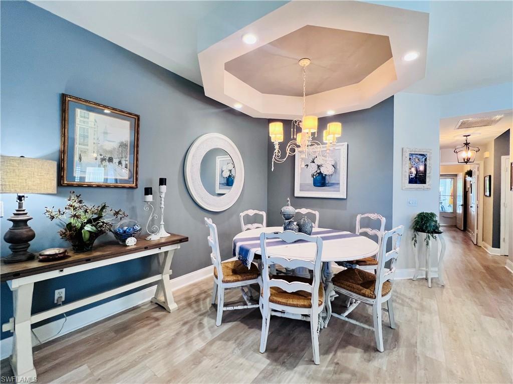3250 West Crown Pointe Boulevard, Unit 101 Naples, FL 34112 - Photo 1 of 46 a dining room with wooden floor and a clock