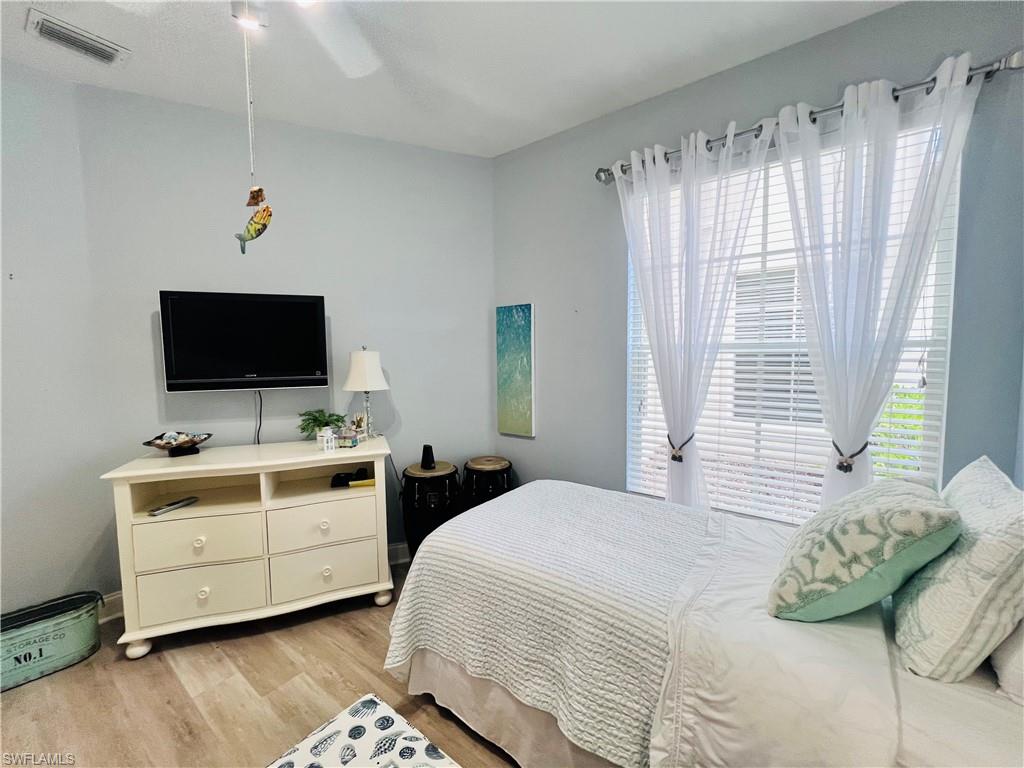 3250 West Crown Pointe Boulevard, Unit 101 Naples, FL 34112 - Photo 22 of 46 a bedroom with a large bed and a flat tv screen on dresser