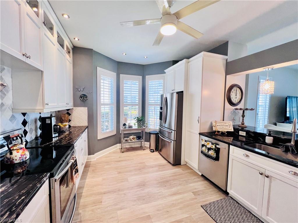 3250 West Crown Pointe Boulevard, Unit 101 Naples, FL 34112 - Photo 3 of 46 a kitchen with a refrigerator a stove a sink dishwasher and white cabinets with wooden floor