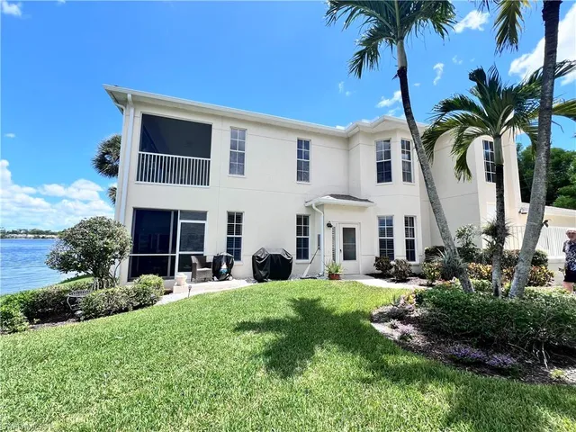 a large white house with a yard and palm trees
