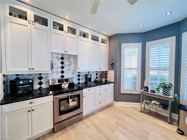 a kitchen with stainless steel appliances a stove a sink and white cabinets
