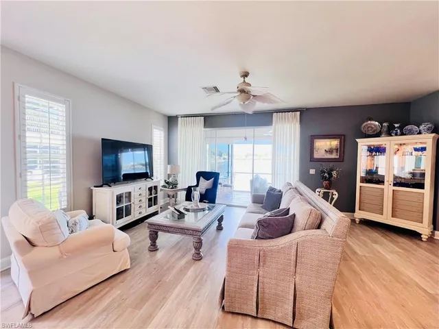 a living room with furniture flat screen tv and a large window