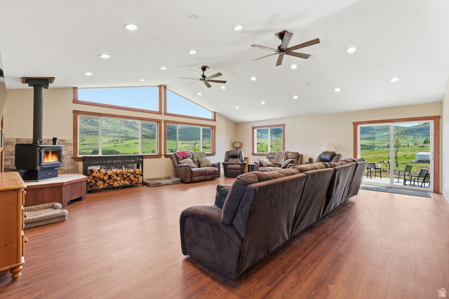 8066 North Valley View Heights Preston, ID 83263 - Photo 5 of 34 Spacious great room featuring wood-finish flooring, a vaulted ceiling with recessed lighting and ceiling fans, and a wood-burning stove with a stone surround