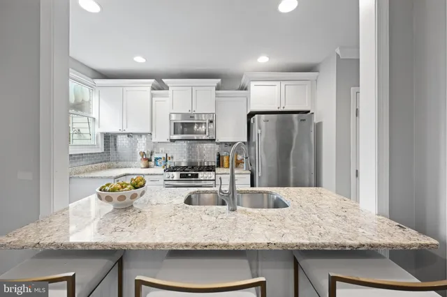 a kitchen with stainless steel appliances granite countertop a sink refrigerator and microwave