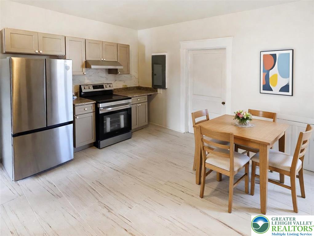 1401 Broadway, Unit 2 Bethlehem, PA 18015 - Photo 2 of 7 a kitchen with stainless steel appliances kitchen island granite countertop a table chairs stove and refrigerator