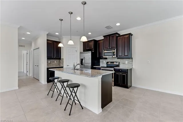 a kitchen with a refrigerator a stove top oven a sink and a chairs