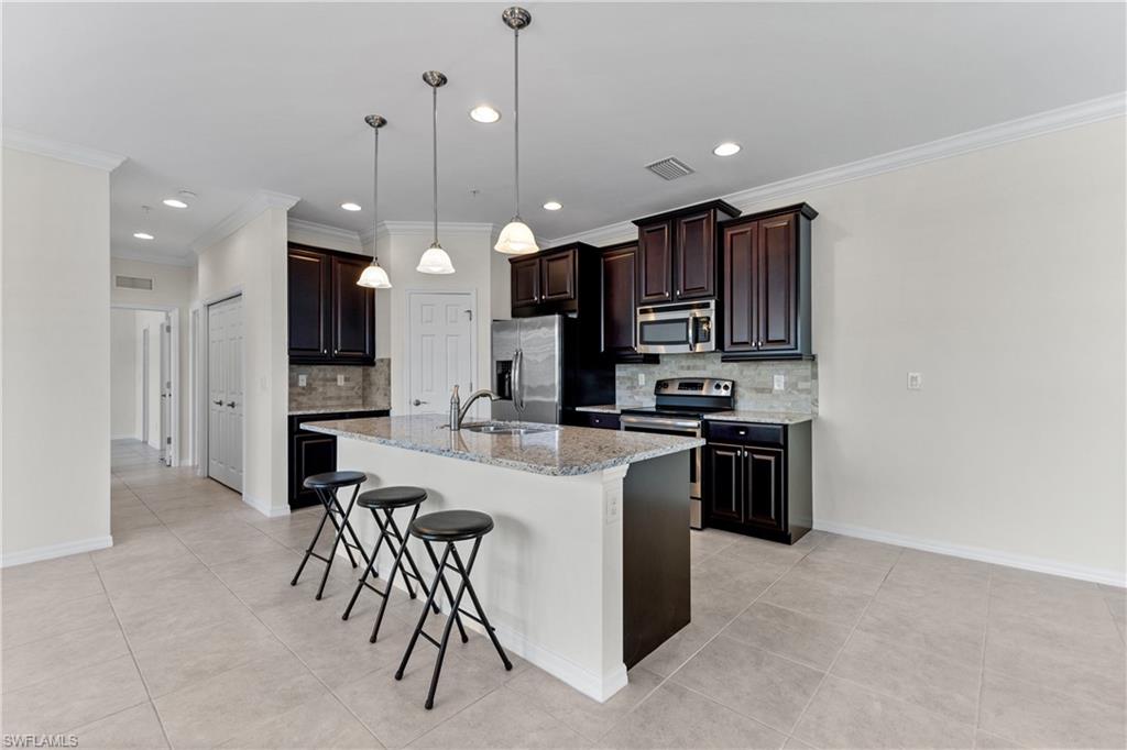 8531 Violeta Street, Unit 203 Estero, FL 34135 - Photo 8 of 35 a kitchen with a refrigerator a stove top oven a sink and a chairs
