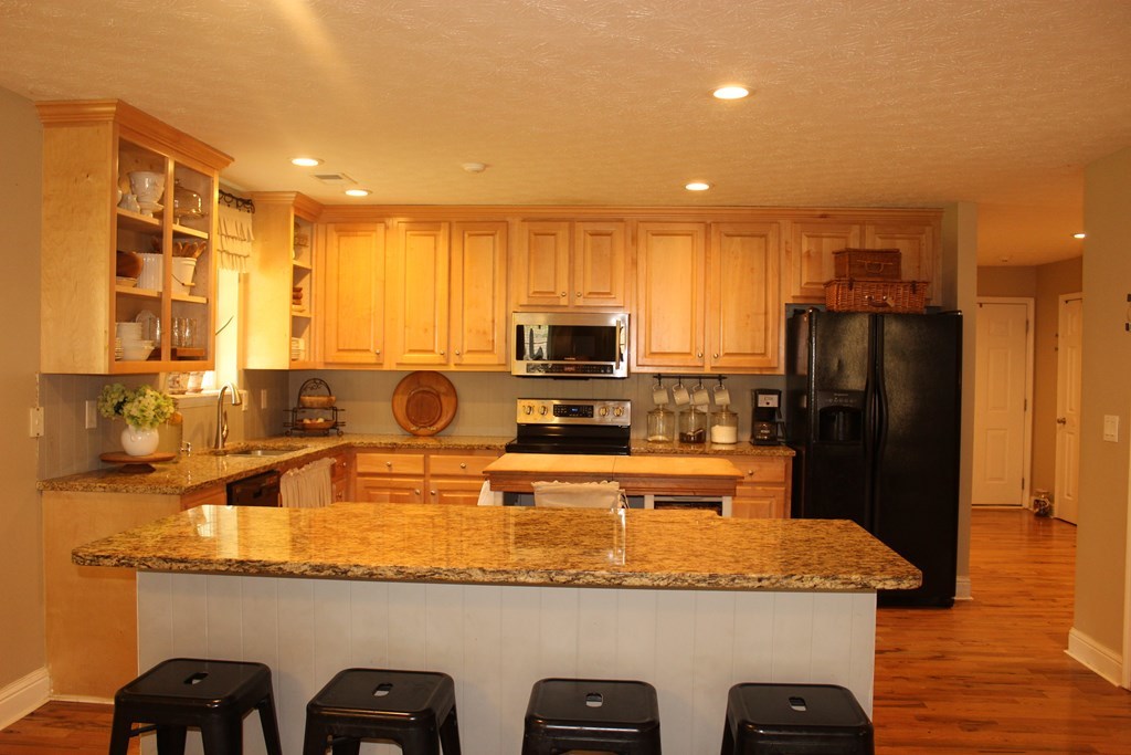 375 Old Cabaniss Road Forsyth, GA 31029 - Photo 4 of 23 a kitchen with kitchen island granite countertop a refrigerator a stove and a sink with wooden floor