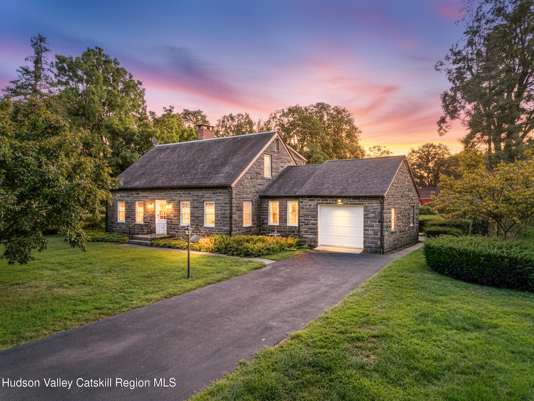 a view of a big house with a big yard and potted plants and large trees
