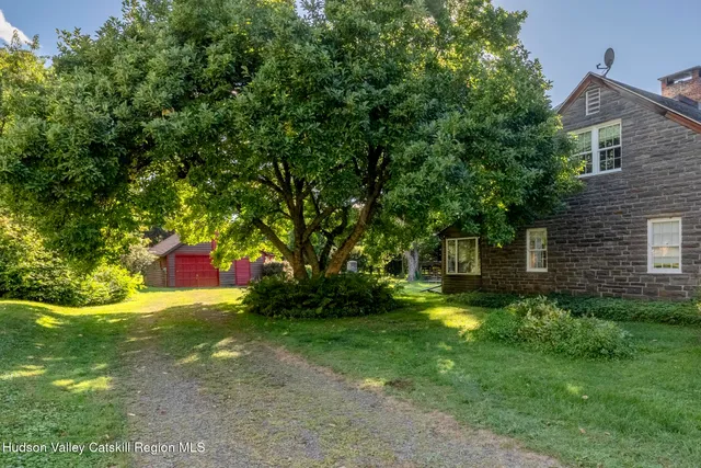 a view of a trees in front of a brick house with a small yard