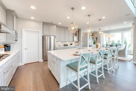 a kitchen with stainless steel appliances kitchen island granite countertop a dining table chairs and sink