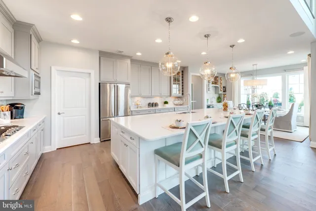 a kitchen with stainless steel appliances kitchen island granite countertop a dining table chairs and sink
