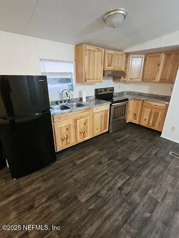 a kitchen with granite countertop wooden cabinets a stove a microwave and a refrigerator