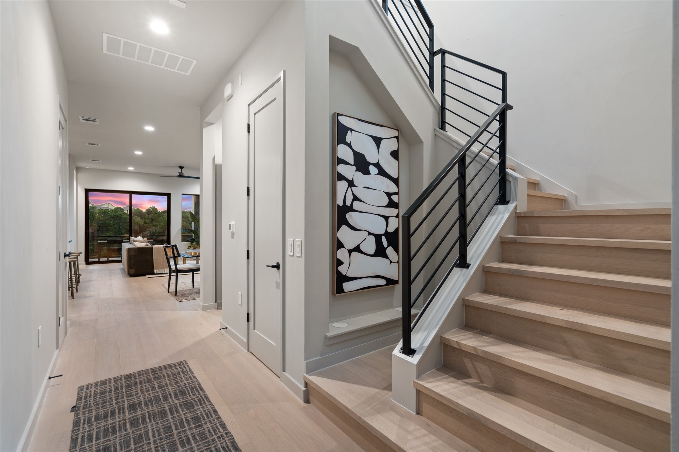 9803 Ribelin Ranch Court, Unit 6 Austin, TX 78750 - Photo 16 of 31 An inviting entry hallway with light hardwood flooring leads to a contemporary staircase with sleek metal railings.