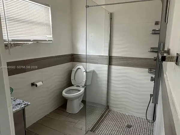 an empty room with wooden floor and a bathroom