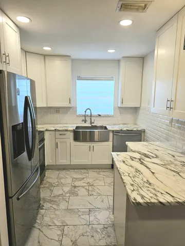 a kitchen with stainless steel appliances granite countertop a sink stove refrigerator and cabinets