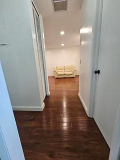 a view of a hallway with wooden floor and furniture