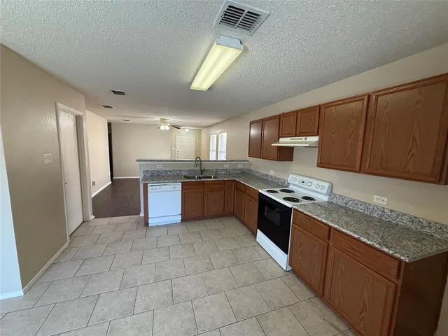 a large kitchen with stainless steel appliances granite countertop a stove a sink dishwasher and a refrigerator