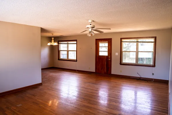 a view of an empty room with window and wooden floor