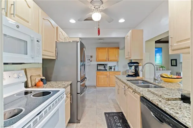 a kitchen with granite countertop a sink a counter space appliances and cabinets