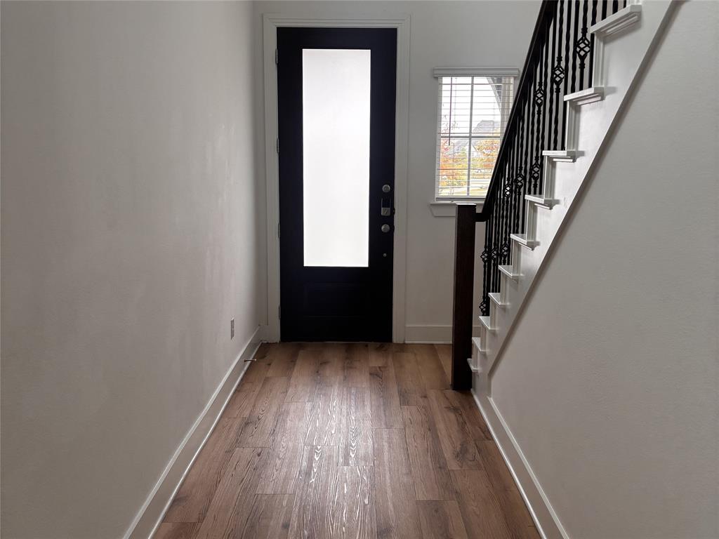2828 Walden Road Celina, TX 75009 - Photo 2 of 30 Entryway featuring wood-finish flooring, a dark-paneled door with frosted glass, and a staircase with decorative metal balusters and a wood handrail
