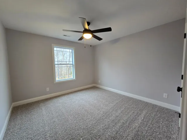 an empty room with a window and a fan