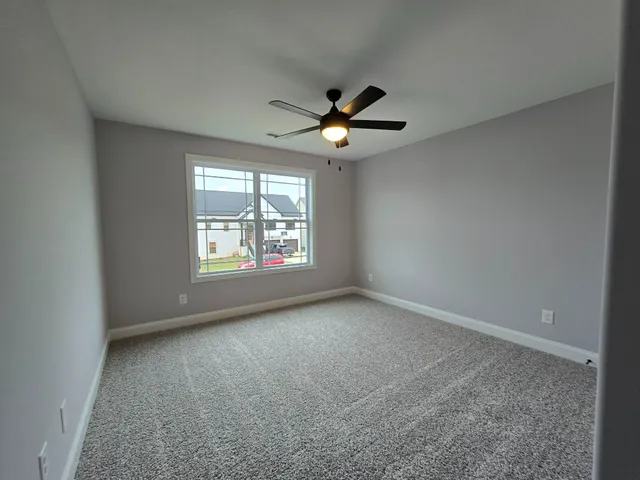 an empty room with windows and ceiling fan