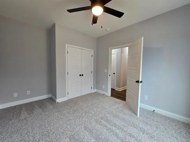 a view of an empty room with window and chandelier fan